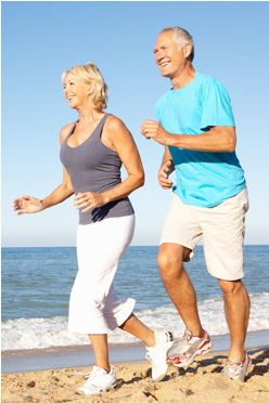 A man and a woman are running along the edge of the beach.